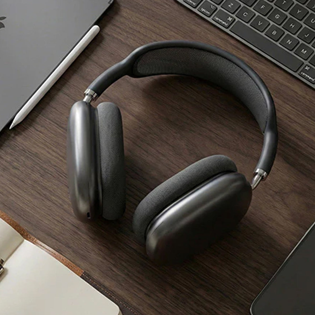 CTRL8 Bluetooth headphones 9P-BM placed on a wooden desk beside a laptop, showcasing a sleek design for work or leisure.