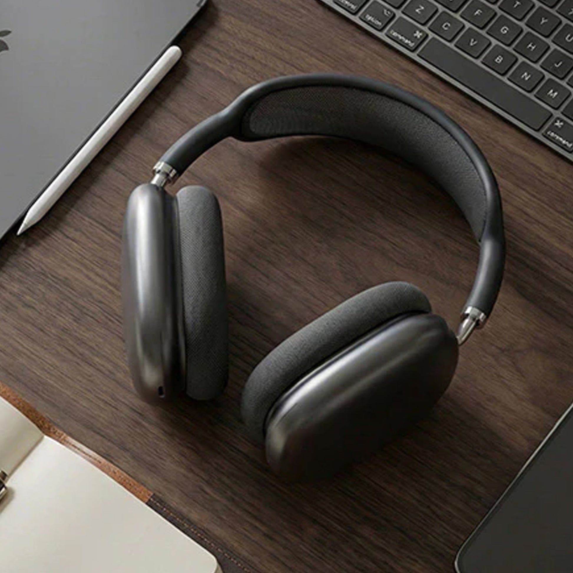 CTRL8 Bluetooth headphones 9P-BM placed on a wooden desk beside a laptop, showcasing a sleek design for work or leisure.