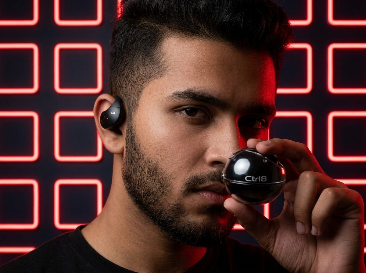 Person using CTRL8 T2 over-the-ear earbuds with UNBLOQ technology against a neon-lit background